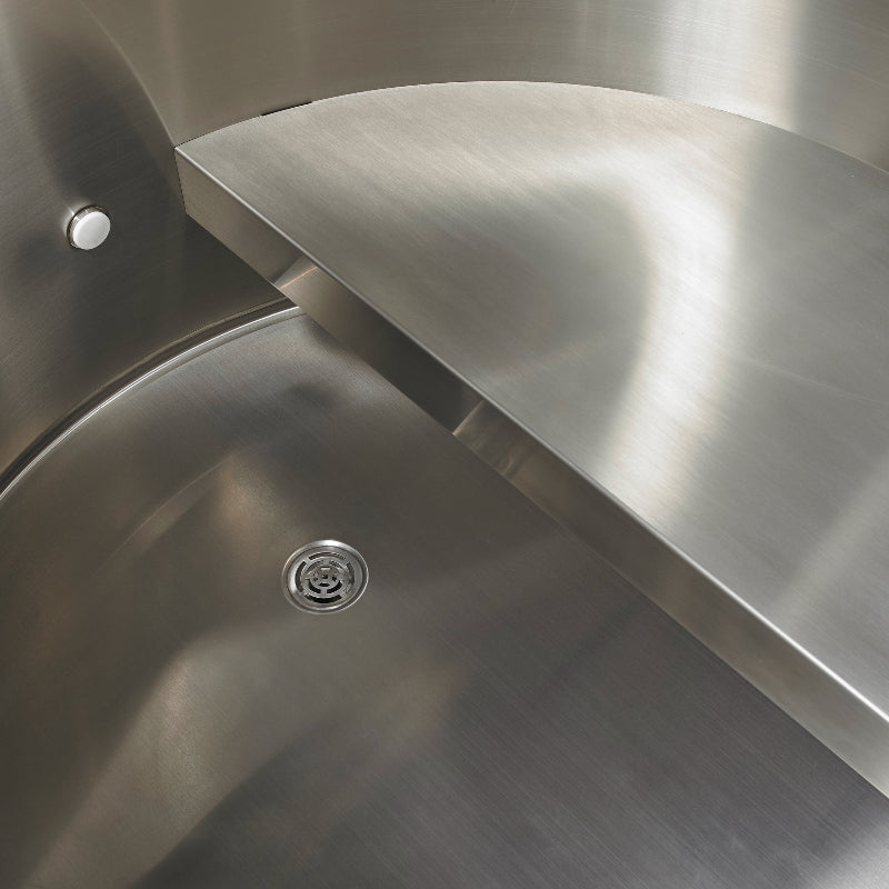 Close-up of a stainless steel cold plunge with a drain.