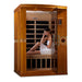 Woman sitting inside a wooden infrared sauna on a white background