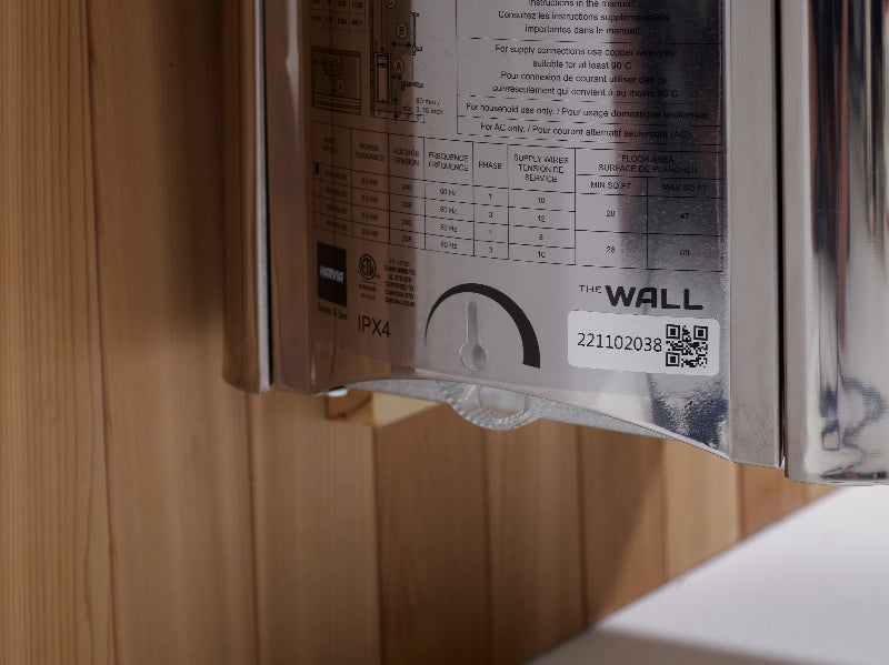 Metallic wall-mounted device with label and QR code on a wooden surface