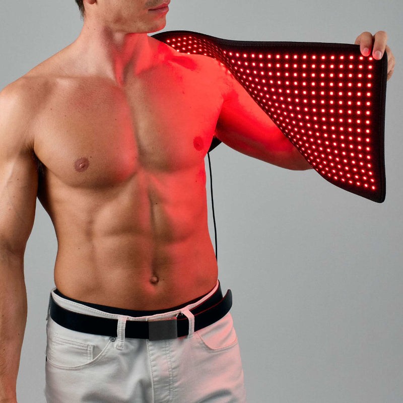 Man using a red light therapy mat on his arm against a gray background