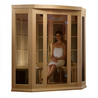 Woman sitting inside a wooden infrared sauna with glass panels.